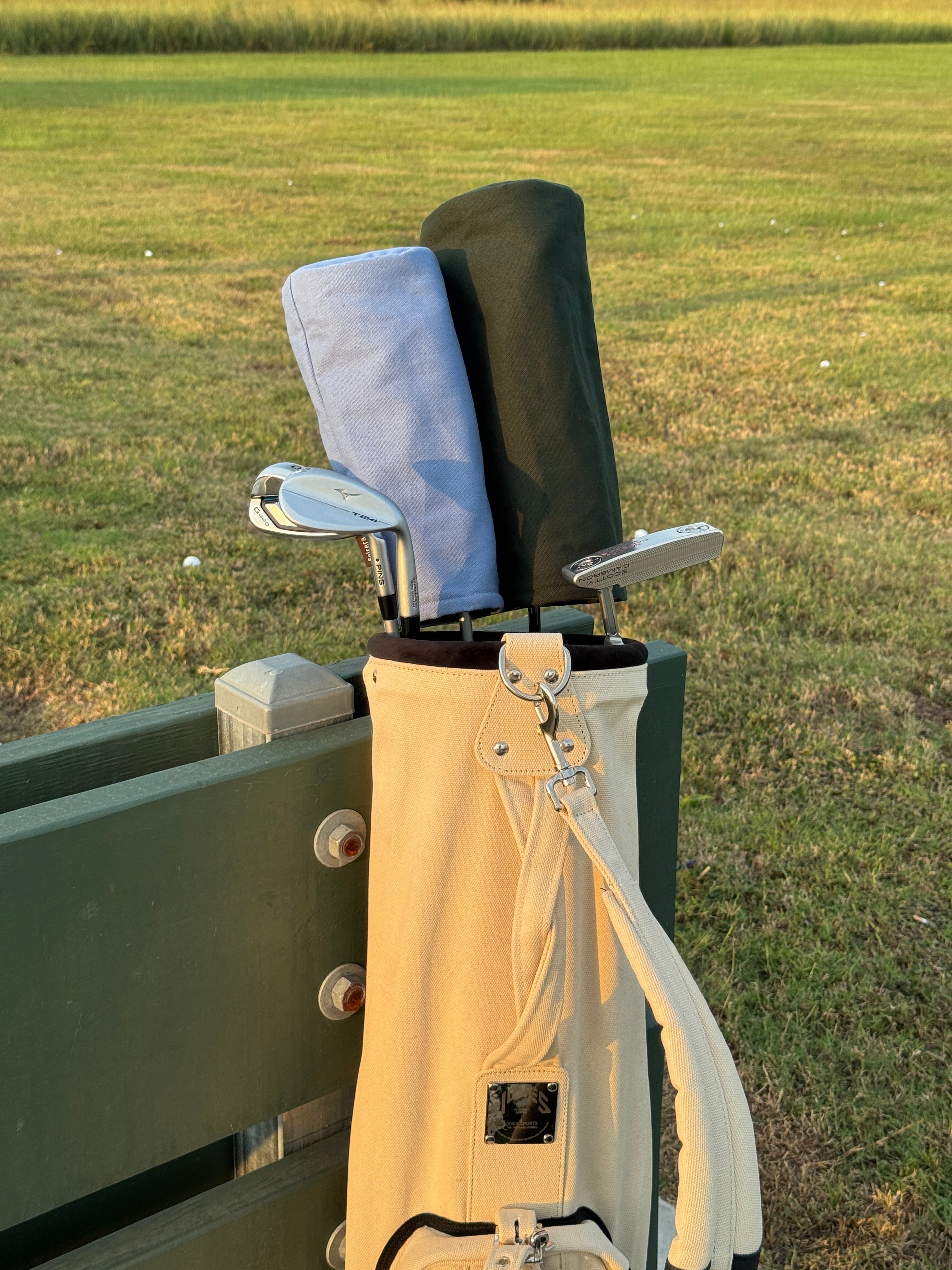 Close-up of a golf club with a beige club head cover on a grassy background