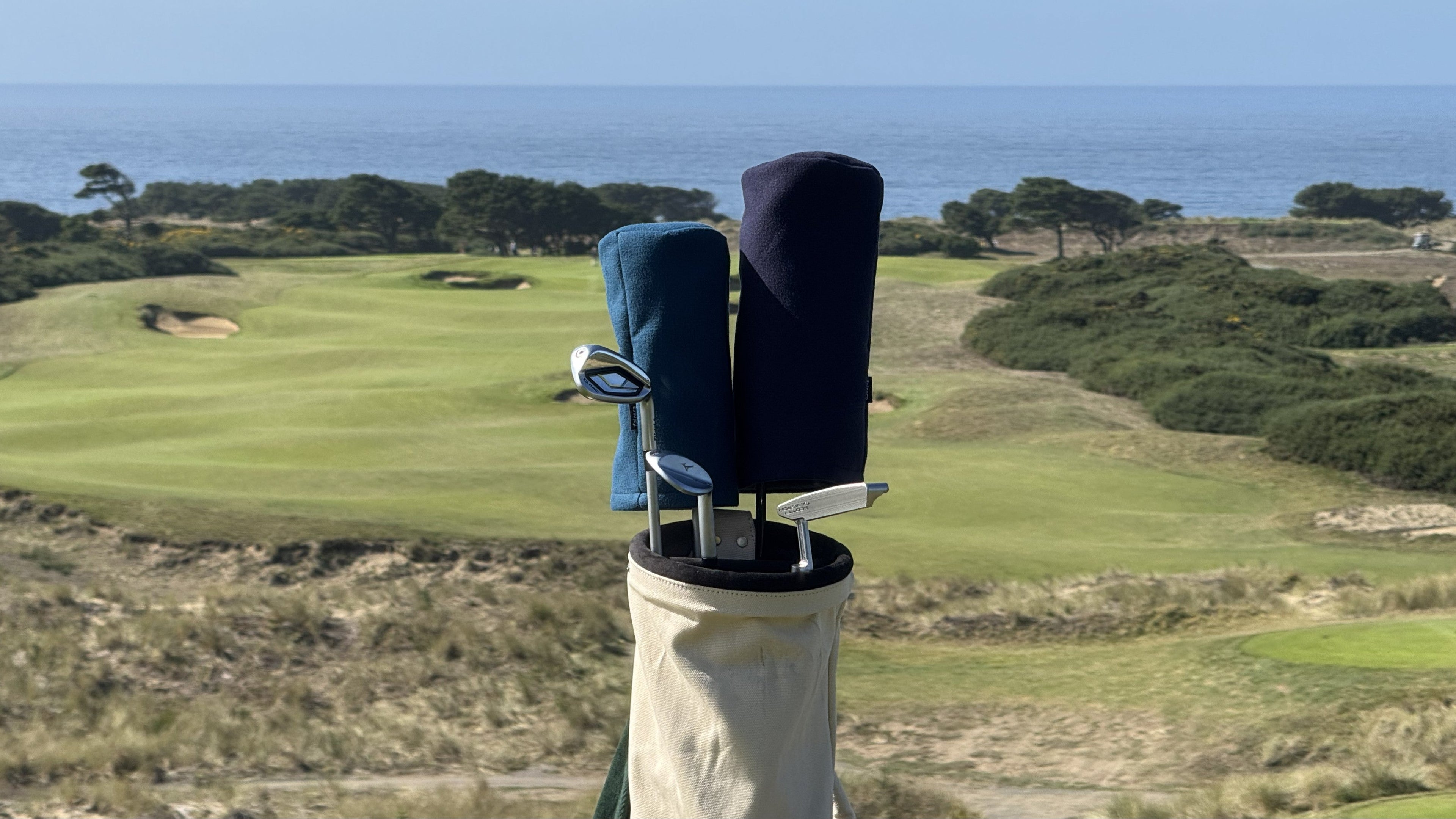 Golf club with covers on a stand overlooking a golf course and ocean.